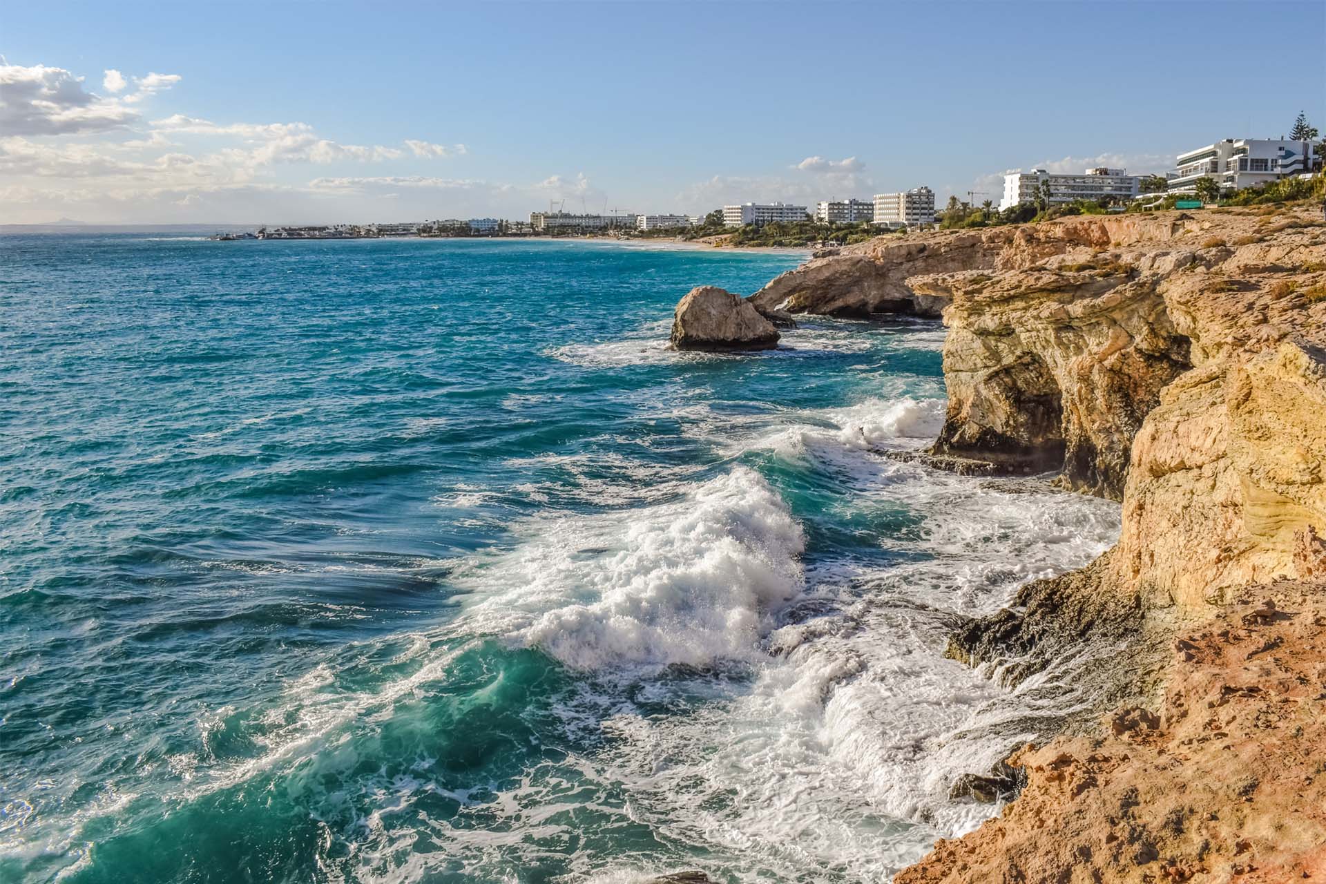 Waves crashing against rocky coastline in Cyprus, travel here with a visa from Prism.