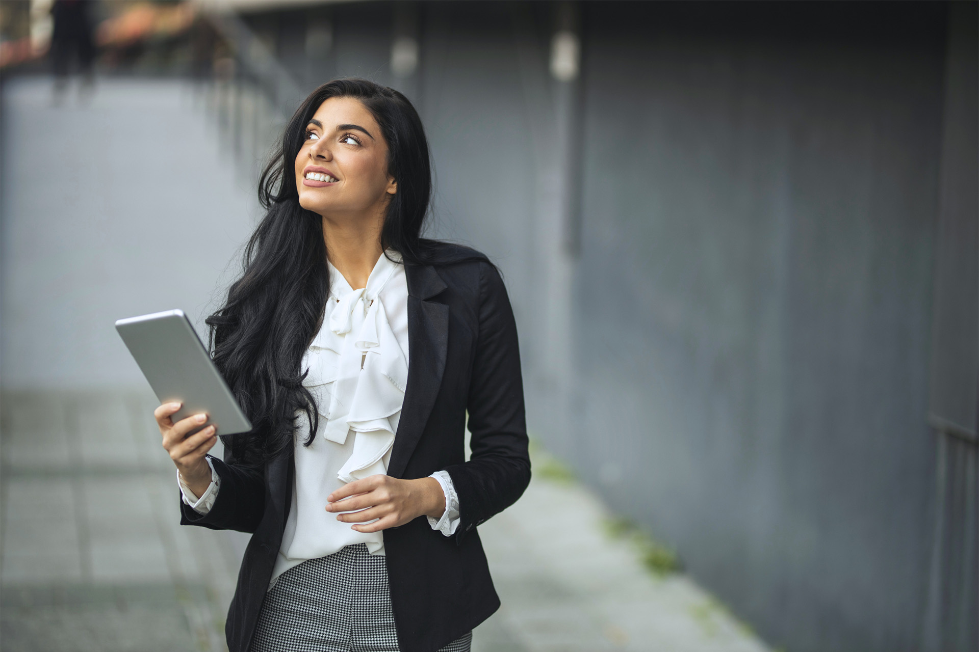 Businesswoman holding tablet outdoors. Get a work visa with Prism.